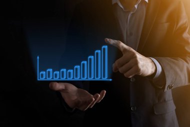 Holografik grafikler ve borsa istatistikleri tutan işadamı kâr elde ediyor. Büyüme planlama ve iş stratejisi kavramı. İyi ekonomi formunun dijital ekran görüntüsü