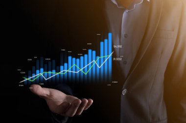 Holografik grafikler ve borsa istatistikleri tutan işadamı kâr elde ediyor. Büyüme planlama ve iş stratejisi kavramı. İyi ekonomi formunun dijital ekran görüntüsü
