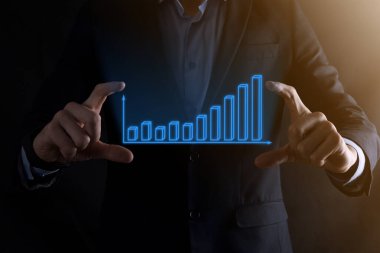 Holografik grafikler ve borsa istatistikleri tutan işadamı kâr elde ediyor. Büyüme planlama ve iş stratejisi kavramı. İyi ekonomi formunun dijital ekran görüntüsü