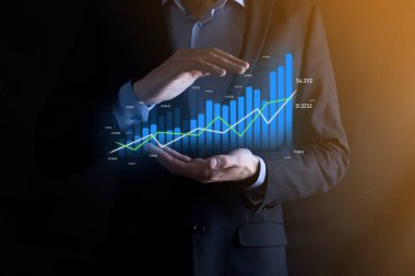 Holografik grafikler ve borsa istatistikleri tutan işadamı kâr elde ediyor. Büyüme planlama ve iş stratejisi kavramı. İyi ekonomi formunun dijital ekran görüntüsü