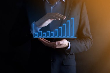 Holografik grafikler ve borsa istatistikleri tutan işadamı kâr elde ediyor. Büyüme planlama ve iş stratejisi kavramı. İyi ekonomi formunun dijital ekran görüntüsü