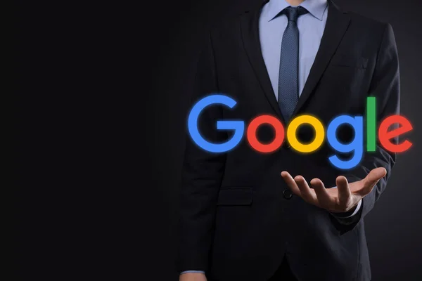 VINOGRADIV, UKRAINE - 30 ARALIK 2020. Karanlık bir geçmişi olan takım elbiseli bir işadamı bir Google logosu tutuyor. Google dünyanın en popüler arama motorudur.