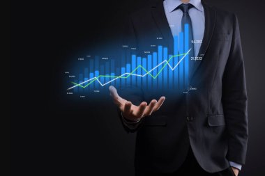 Holografik grafikler ve borsa istatistikleri tutan işadamı kâr elde ediyor. Büyüme planlama ve iş stratejisi kavramı. İyi ekonomi formunun dijital ekran görüntüsü