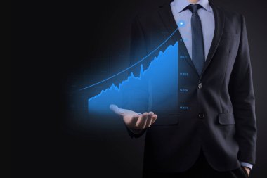 Holografik grafikler ve borsa istatistikleri tutan işadamı kâr elde ediyor. Büyüme planlama ve iş stratejisi kavramı. İyi ekonomi formunun dijital ekran görüntüsü