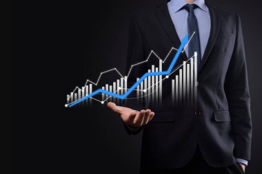 Holografik grafikler ve borsa istatistikleri tutan işadamı kâr elde ediyor. Büyüme planlama ve iş stratejisi kavramı. İyi ekonomi formunun dijital ekran görüntüsü