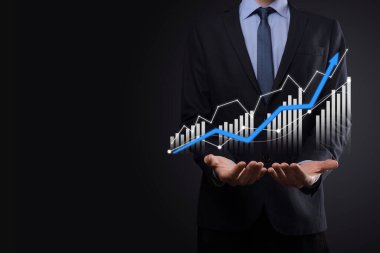 Holografik grafikler ve borsa istatistikleri tutan işadamı kâr elde ediyor. Büyüme planlama ve iş stratejisi kavramı. İyi ekonomi formunun dijital ekran görüntüsü
