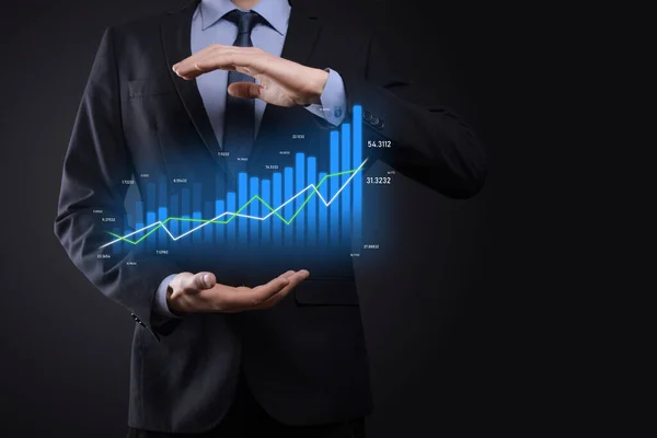 Business man holding holographic graphs and stock market statistics gain profits. Concept of growth planning and business strategy. Display of good economy form digital screen