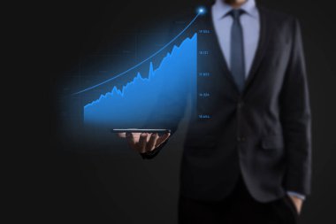 Holografik grafikler ve borsa istatistikleri tutan işadamı kâr elde ediyor. Büyüme planlama ve iş stratejisi kavramı. İyi ekonomi formunun dijital ekran görüntüsü