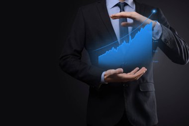 Holografik grafikler ve borsa istatistikleri tutan işadamı kâr elde ediyor. Büyüme planlama ve iş stratejisi kavramı. İyi ekonomi formunun dijital ekran görüntüsü