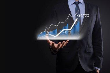 Holografik grafikler ve borsa istatistikleri tutan işadamı kâr elde ediyor. Büyüme planlama ve iş stratejisi kavramı. İyi ekonomi formunun dijital ekran görüntüsü