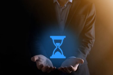 İş adamı elinde kum saati ikonu tutuyor. Zaman doluyor. Harekete geçmek için bir hatırlatma. İş konsepti. Tasarım için elementler