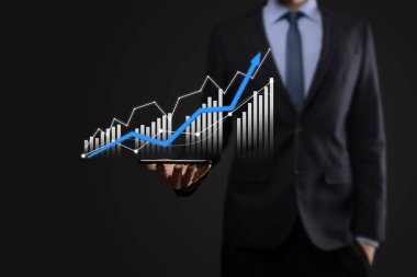 Holografik grafikler ve borsa istatistikleri tutan işadamı kâr elde ediyor. Büyüme planlama ve iş stratejisi kavramı. İyi ekonomi formunun dijital ekran görüntüsü