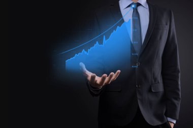 Holografik grafikler ve borsa istatistikleri tutan işadamı kâr elde ediyor. Büyüme planlama ve iş stratejisi kavramı. İyi ekonomi formunun dijital ekran görüntüsü
