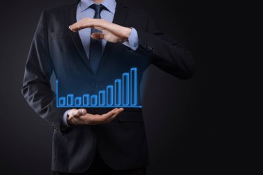 Holografik grafikler ve borsa istatistikleri tutan işadamı kâr elde ediyor. Büyüme planlama ve iş stratejisi kavramı. İyi ekonomi formunun dijital ekran görüntüsü