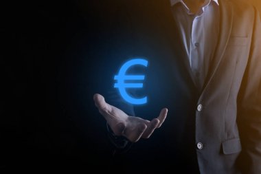 İş adamı, para sikkesi ikonlarını koyu tonda arka planda tutar iş yatırımları ve finans için büyüyen para kavramına sahiptir..