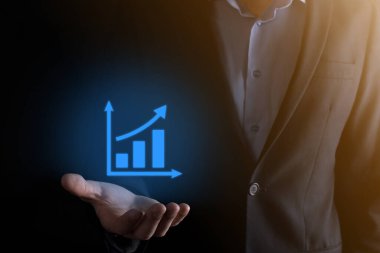 İş adamı elinde pozitif kar artışı olan bir grafik tutuyor. Grafik büyümesi ve grafik artışı işlerinde olumlu göstergeler. Daha kârlı ve büyüyen