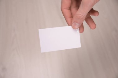 İş adamı, iş adamının el ele tutuşması. Gri arka planda yakın plan görüntüsü var. Boş bir kağıt parçası göster. Kağıt ziyareti kartı.