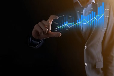 İş adamı holografik grafikler ve borsa istatistikleri tutuyor ve gösteriyor. Büyüme planlama ve iş stratejisi kavramı. İyi ekonomi formunun dijital ekran görüntüsü