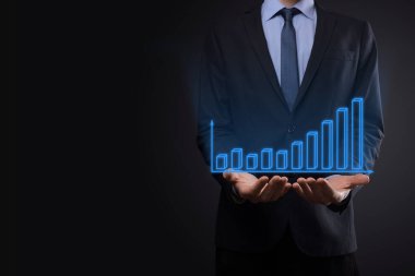 Holografik grafikler ve borsa istatistikleri tutan işadamı kâr elde ediyor. Büyüme planlama ve iş stratejisi kavramı. İyi ekonomi formunun dijital ekran görüntüsü