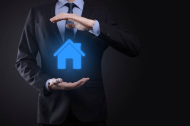 Emlak konsepti, iş adamı ev ikonu tutuyor. Ev elden gidiyor. Emlak sigortası ve güvenlik kavramı. İnsanın jestini ve evin sembolünü koruyorum.
