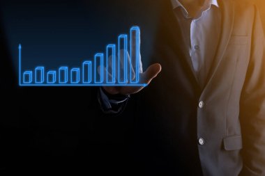 Holografik grafikler ve borsa istatistikleri tutan işadamı kâr elde ediyor. Büyüme planlama ve iş stratejisi kavramı. İyi ekonomi formunun dijital ekran görüntüsü