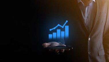İş adamı elinde pozitif kar artışı olan bir grafik tutuyor. Grafik büyümesi ve grafik artışı işlerinde olumlu göstergeler. Daha kârlı ve büyüyen