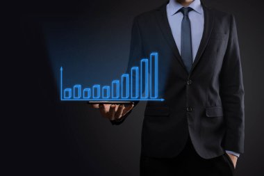 Holografik grafikler ve borsa istatistikleri tutan işadamı kâr elde ediyor. Büyüme planlama ve iş stratejisi kavramı. İyi ekonomi formunun dijital ekran görüntüsü