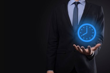İş adamı, saatin simgesini okla tutar. İşlerin hızlı yürütülmesi. İş zamanı yönetimi ve iş zamanı para kavramlarıdır..