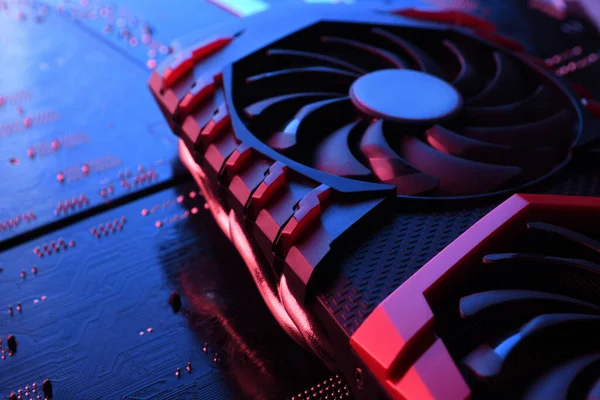 Computer game graphics card, videocard with two coolers on circuit board ,motherboard background. Close-up. With red-blue a lighting.