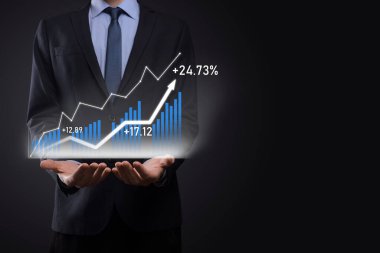 Holografik grafikler ve borsa istatistikleri tutan işadamı kâr elde ediyor. Büyüme planlama ve iş stratejisi kavramı. İyi ekonomi formunun dijital ekran görüntüsü