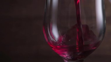Koyu arkaplanda kırmızı şarap sallıyor. Şarap reklamı için çok güzel görüntüler. Yavaş Hareket .