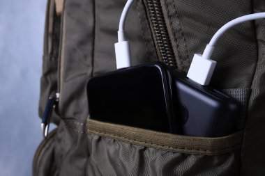 Telefon şarjı, elektrik faturası akıllı telefon, enerji bankasıyla cep telefonu. Sırt çantasındaki Güç Bankası 'nın derinliği