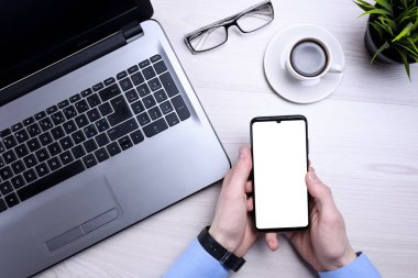 İş adamı, adam dizüstü bilgisayarda çalışıyor ve cep telefonu kullanıyor. Manzara, akıllı telefon, bardaklar, kahve. Model.