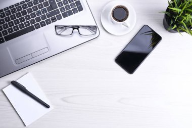 Bilgisayarlı masa masası, akıllı telefon, bir fincan kahve ve malzeme, ahşap arka planda. Kopyalama alanı olan üst görünüm, düz yatay
