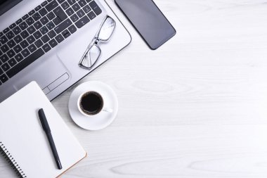 Bilgisayarlı masa masası, akıllı telefon, bir fincan kahve ve malzeme, ahşap arka planda. Kopyalama alanı olan üst görünüm, düz yatay