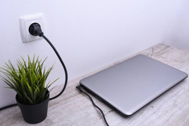 Laptop, bilgisayar duvarın yanındaki bir masada 220 voltluk bir prizden şarj oluyor. Enerji, birikim
