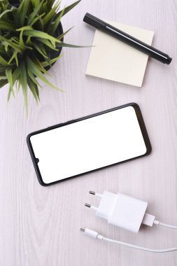 Metnin için beyaz ekranlı cep telefonu akıllı telefonu, şarj edilmiş parlak arızalı bir tablo üzerindeki resim