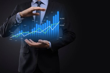 Holografik grafikler ve borsa istatistikleri tutan işadamı kâr elde ediyor. Büyüme planlama ve iş stratejisi kavramı. İyi ekonomi formunun dijital ekran görüntüsü