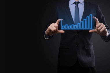 Holografik grafikler ve borsa istatistikleri tutan işadamı kâr elde ediyor. Büyüme planlama ve iş stratejisi kavramı. İyi ekonomi formunun dijital ekran görüntüsü