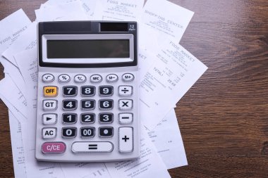 Ahşap zemin üzerinde mağazadan alınmış çeklerle hesaplayıcı tuş takımı. Üst Manzara. Boşluğu kopyala