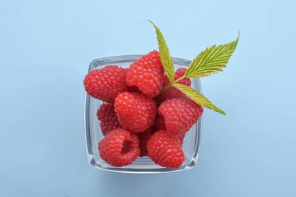 Bowl Van Verse Frambozen Met Groene Bladeren Blauwe Achtergrond Bovenaanzicht — Stockfoto