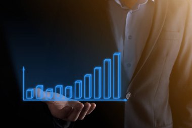 Holografik grafikler ve borsa istatistikleri tutan işadamı kâr elde ediyor. Büyüme planlama ve iş stratejisi kavramı. İyi ekonomi formunun dijital ekran görüntüsü