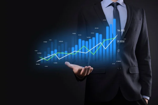 Business man holding holographic graphs and stock market statistics gain profits. Concept of growth planning and business strategy. Display of good economy form digital screen