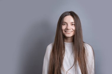 Güzel, neşeli, siyah saçlı, sıradan giyinmiş, kameraya tatmin edici bir şekilde bakan, mutlu bir kadın. Güzel bir kadının stüdyo resmi. Boş bir stüdyo duvarında izole edilmiş.