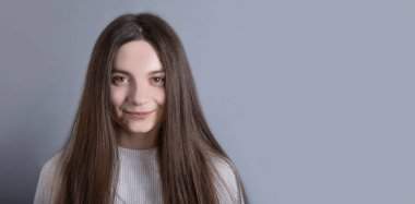 Güzel, neşeli, siyah saçlı, sıradan giyinmiş, kameraya tatmin edici bir şekilde bakan, mutlu bir kadın. Güzel bir kadının stüdyo resmi. Boş bir stüdyo duvarında izole edilmiş.