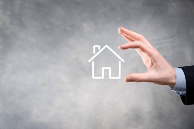 Emlak konsepti, iş adamı ev ikonu tutuyor. Ev elden gidiyor. Emlak sigortası ve güvenlik kavramı. İnsanın jestini ve evin sembolünü koruyorum..