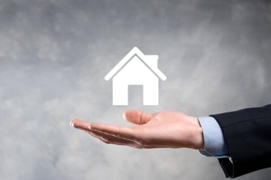 Emlak konsepti, iş adamı ev ikonu tutuyor. Ev elden gidiyor. Emlak sigortası ve güvenlik kavramı. İnsanın jestini ve evin sembolünü koruyorum..