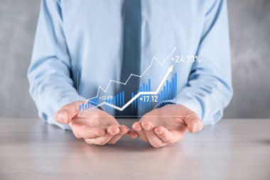 İş adamı elinde pozitif kar artışı olan bir grafik tutuyor. Grafik büyümesi ve grafik artışı işlerinde olumlu göstergeler. Daha kârlı ve büyüyen.