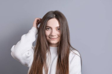 Güzel, neşeli, siyah saçlı, sıradan giyinmiş, kameraya tatmin edici bir şekilde bakan, mutlu bir kadın. Güzel bir kadının stüdyo resmi. Boş bir stüdyo duvarında izole edilmiş.