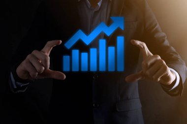 İş adamı elinde pozitif kar artışı olan bir grafik tutuyor. Grafik büyümesi ve grafik artışı işlerinde olumlu göstergeler. Daha kârlı ve büyüyen